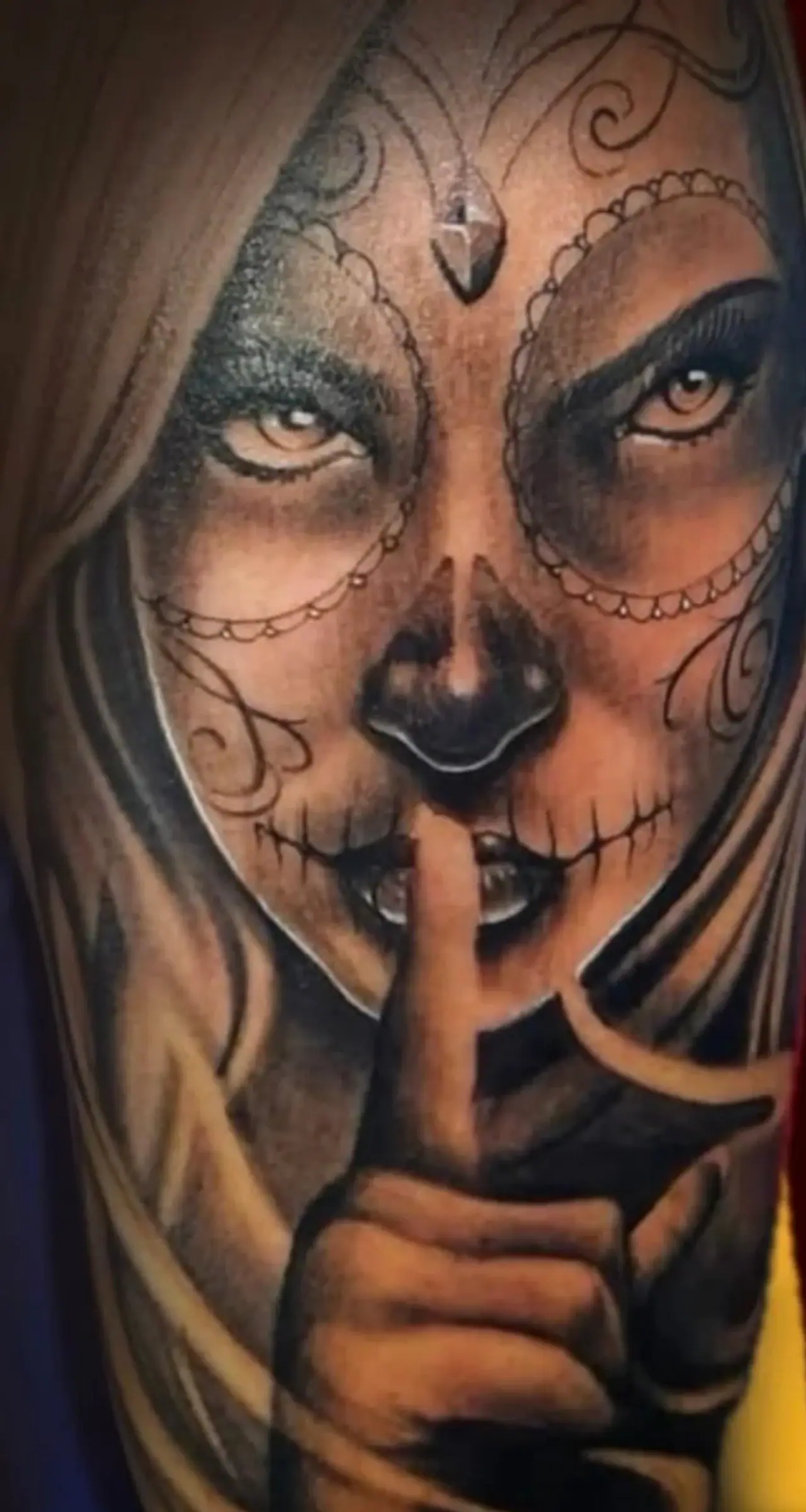Tatuagem realista de Catrina fazendo sinal de silêncio