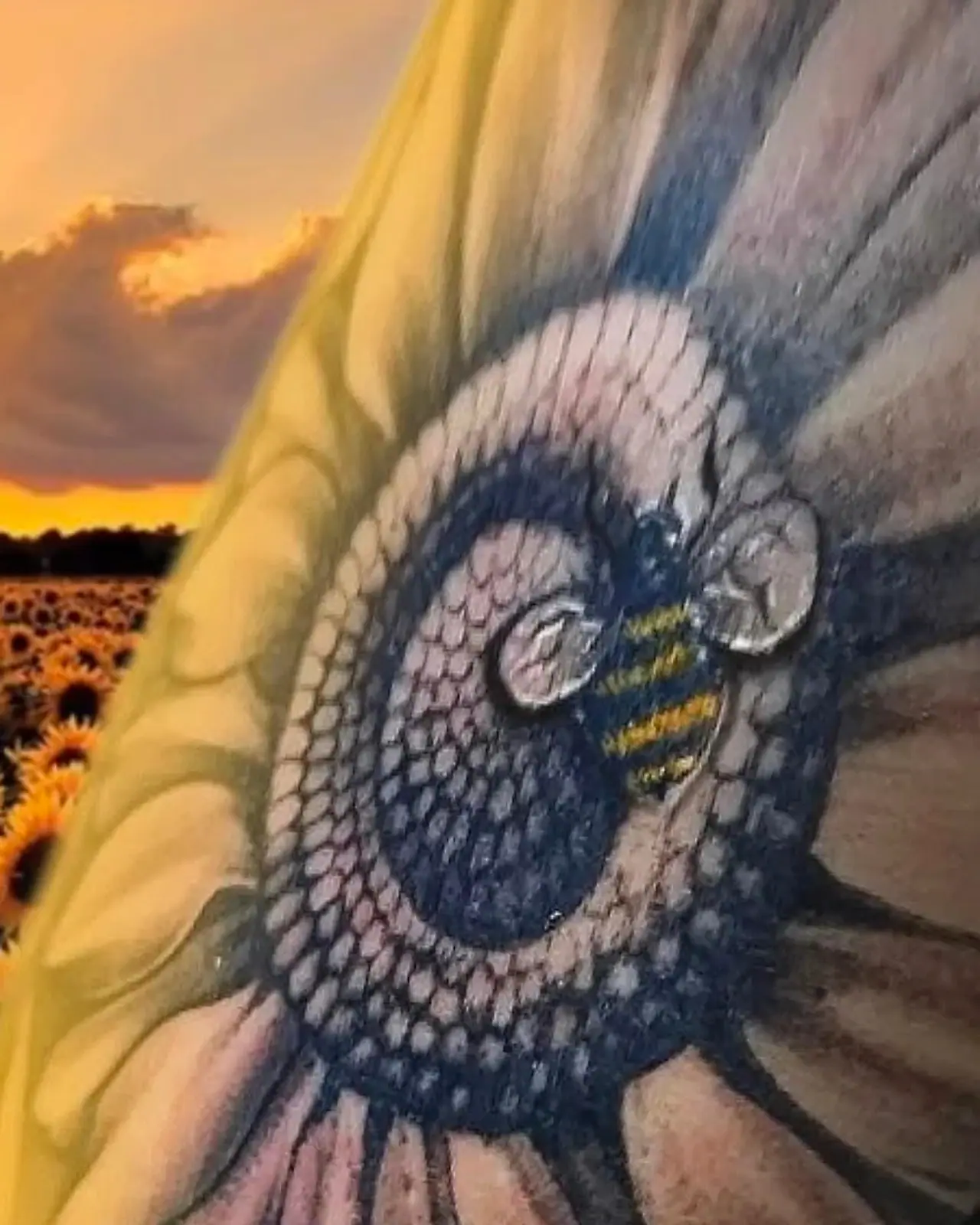 Tatuagem colorida de abelha pousada no miolo de um girassol